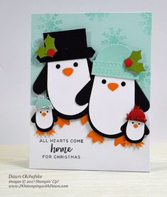 a hand holding up a christmas card with two penguins