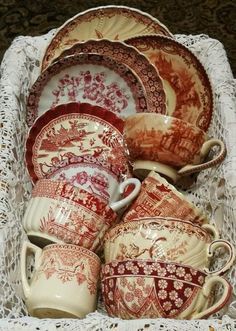 an assortment of red and white china dishes in a lace basket on top of a doily