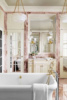 a bath tub sitting under two mirrors in a bathroom