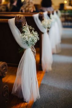 the flowers are tied to the pews at the wedding ceremony in white tulle