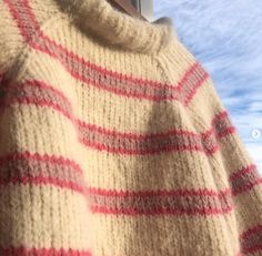 a sweater with red and white stripes is hanging on a window sill in front of a blue sky