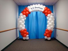 an archway decorated with red, white and blue balloons