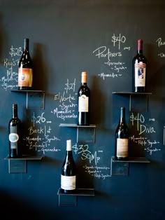 several bottles of wine are lined up on the wall in front of a chalkboard