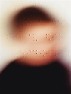 a blurry image of a person's face in front of a window with drops of water on it