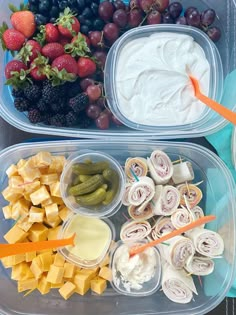 two plastic containers filled with fruit, crackers and dip next to other food items