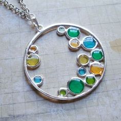 a silver necklace with multicolored glass beads hanging from it's center circle