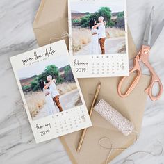 two wedding save the dates cards and scissors on top of an envelope with a couple holding each other