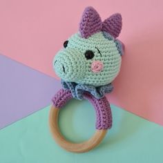 a crocheted animal ring on top of a pink and blue background with a wooden toy