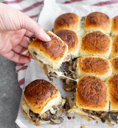 a close up of a person holding a slider with mushrooms on it and text overlay that reads vegetarian cheesy mushroom sliders