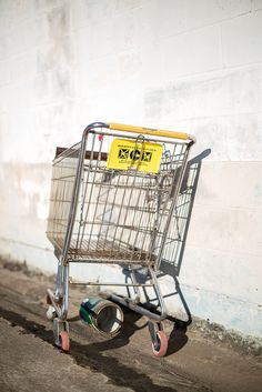 a shopping cart sitting on the side of a building with a yellow sign in it