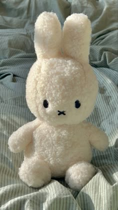 a white stuffed animal sitting on top of a bed