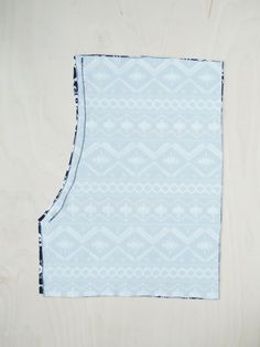 a piece of cloth with a blue and white pattern on the front, sitting on top of a wooden surface