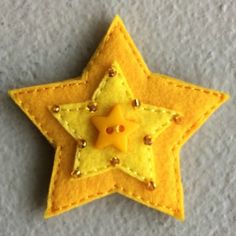 a yellow felt star with studs on the bottom is laying on a gray surface