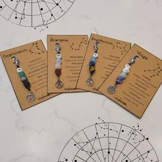 four zodiac necklaces are shown on top of an astrological table with information about them