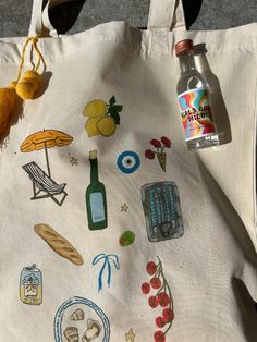 a tote bag with various items on it and a bottle of water next to it