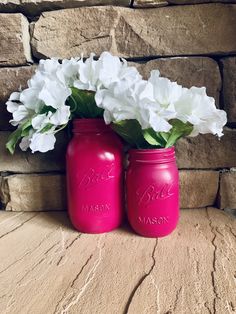 two pink mason jars with white flowers in them