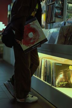 a man standing in front of a record store holding a box with cds on it