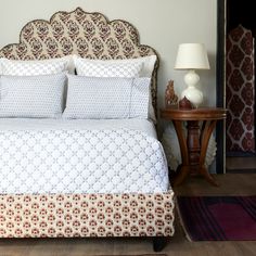 a bed with white and brown bedspread next to a lamp on a table