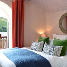 a bed with pillows and blankets on top of it in a bedroom next to a window