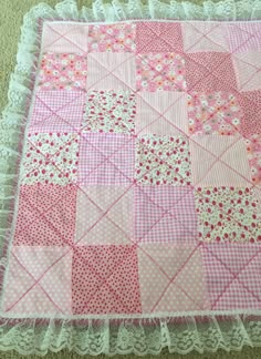 a pink and white patchwork quilt on the floor