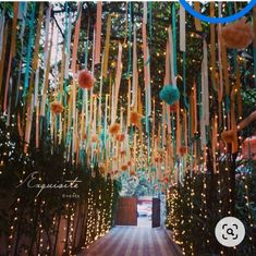 an outdoor walkway with lights hanging from the ceiling and pom - poms on the trees