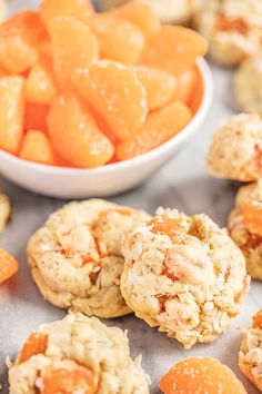 several cookies with oranges in the background and a bowl of candies next to them