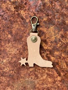 a metal keychain with a cowboy boot and star on it sitting on a rusty surface