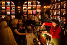 a group of people sitting at a bar in front of shelves full of liquor bottles