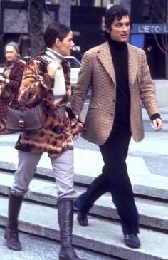 a man and woman walking down the street with handbags on their backs, one carrying a purse