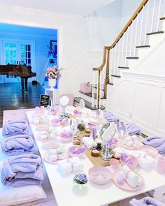 a room filled with lots of baby items on top of a white table next to a stair case