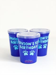 three blue cups with paw prints on them and the words ravion's 1st birthday