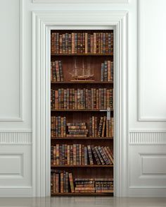 an open bookcase with many books on it in a room that has white walls