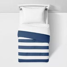 a bed with blue and white striped comforter on top of it next to a wall