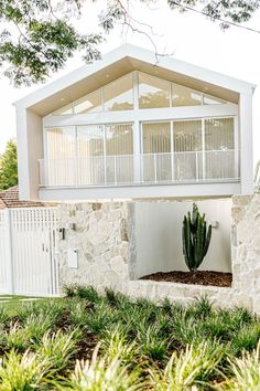 a house with a cactus in front of it and a white fence around the yard