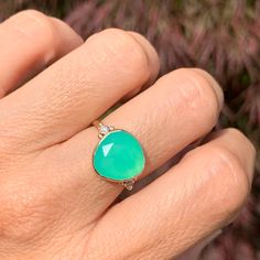 a woman's hand with a green ring on it