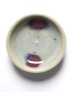 a white bowl with red and blue designs on it's rim, sitting on a white surface