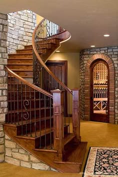 a spiral staircase in a home with stone walls and wood railings leading to the second floor