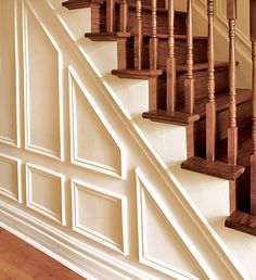 a wooden staircase with white walls and wood handrails