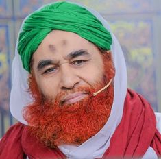 a man with a green turban and red beard wearing a white headdress