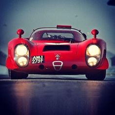 a red sports car driving down the road with its lights on and headlight on