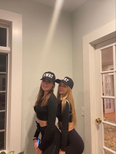 two beautiful young women standing next to each other in front of a door wearing matching hats