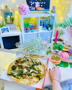 a pizza sitting on top of a white table next to a vase filled with flowers