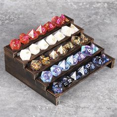 a set of seven dice sitting on top of a wooden holder filled with different colored dice