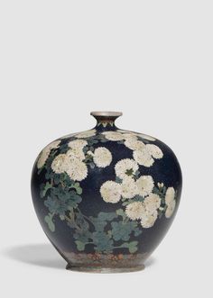 a black vase with white flowers painted on it