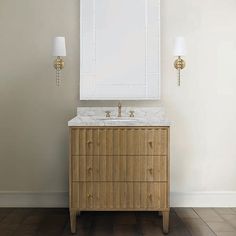 a bathroom vanity with a mirror above it and two lights on the wall next to it