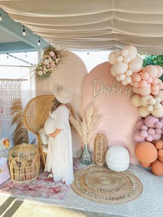 a woman standing in front of a backdrop with balloons and other decorations on it's sides