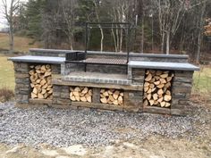 an outdoor grill with firewood stacked on it