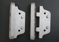 two metal latches on the side of a black wall, one is open and the other is closed