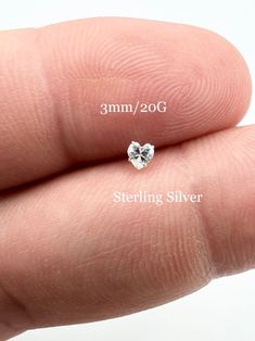 a tiny diamond is sitting on the finger of someone's hand, showing it's size