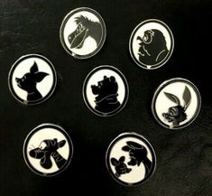 six disney pinbacks on a black surface